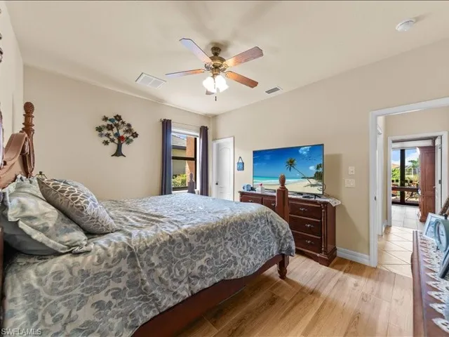 Bedroom with light wood finished floors, multiple windows, and ceiling fan
