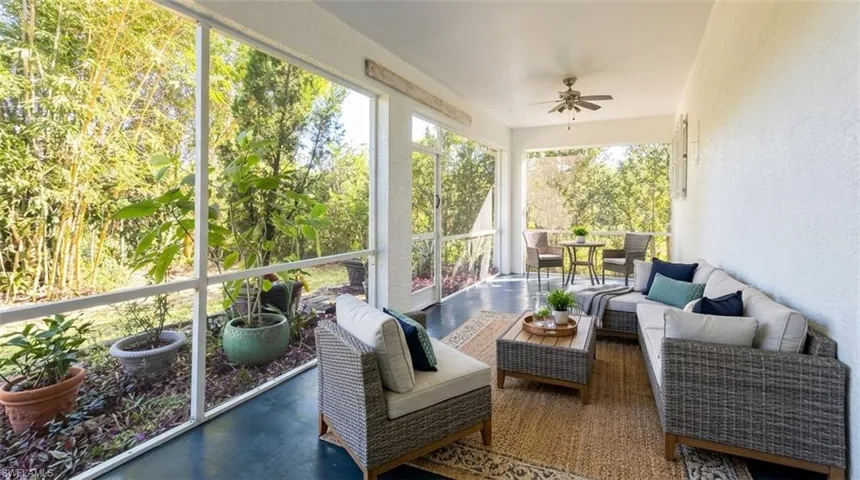 Screened-in porch featuring a painted concrete floor, white metal framing, ceiling fan, and access to exterior grounds
