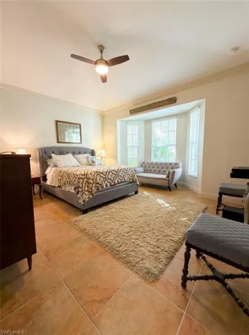 Spacious room featuring large-format tile flooring, a multi-pane bay window, and a central ceiling fan with an integrated light fixture