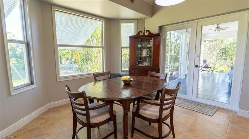 Neutral-toned room featuring large windows, stone-finish tile flooring, and glass-paneled double doors