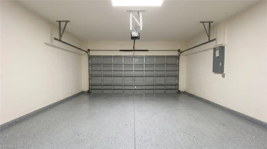 Two-car garage featuring a sectional metal door, epoxy-coated flooring, and an integrated electric door opener