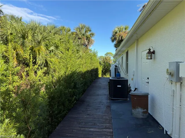 Stucco exterior siding, attached wood-plank walkway, and exterior wall-mounted lighting fixture