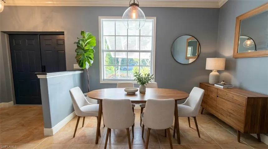 Dining area featuring tile flooring, a multi-pane window, half-wall partition with a dark-finish door, and a glass globe pendant light fixture