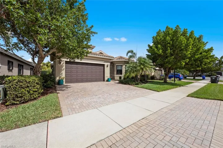 View of front of property featuring a garage, stucco siding, a tile roof, decorative driveway, and a front yard