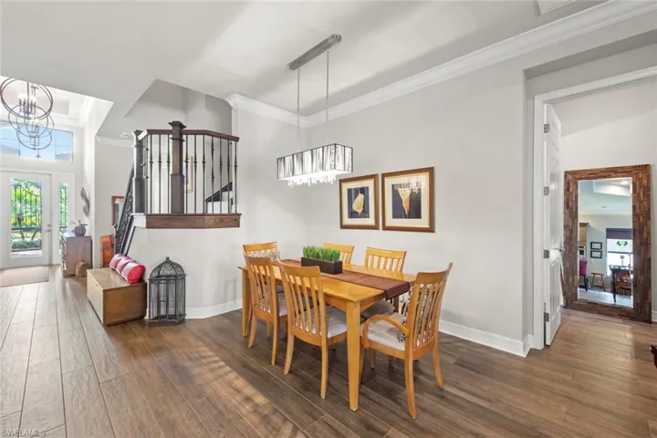 Dining space with wood finished floors, crown molding, and an inviting chandelier