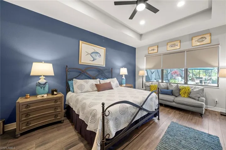 Bedroom with baseboards, a ceiling fan, wood finished floors, a tray ceiling, and recessed lighting