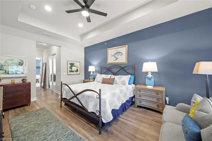 Bedroom featuring a raised ceiling, visible vents, baseboards, and wood finished floors