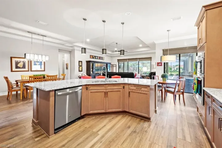 Kitchen with crown molding, light wood-style flooring, open floor plan, and dishwasher