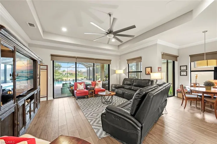 Living room featuring a sliding door to lanai, light wood-style flooring, a raised ceiling