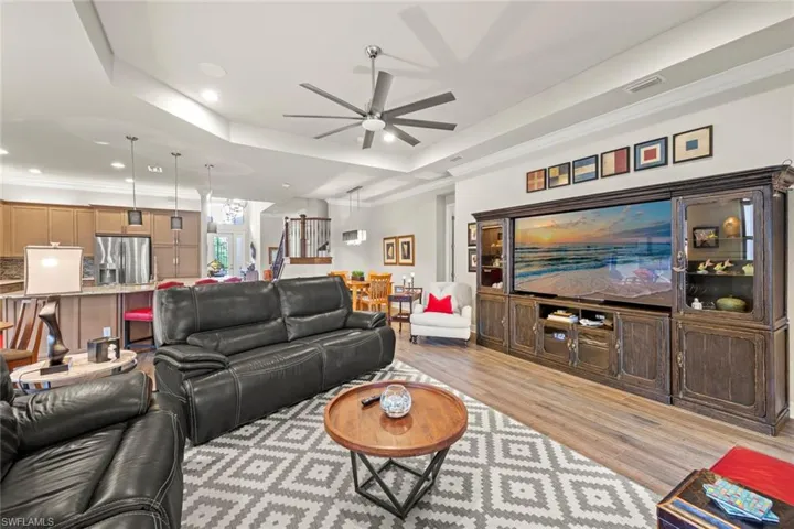 Living area with a tray ceiling, light wood finished floors, recessed lighting, and ornamental molding