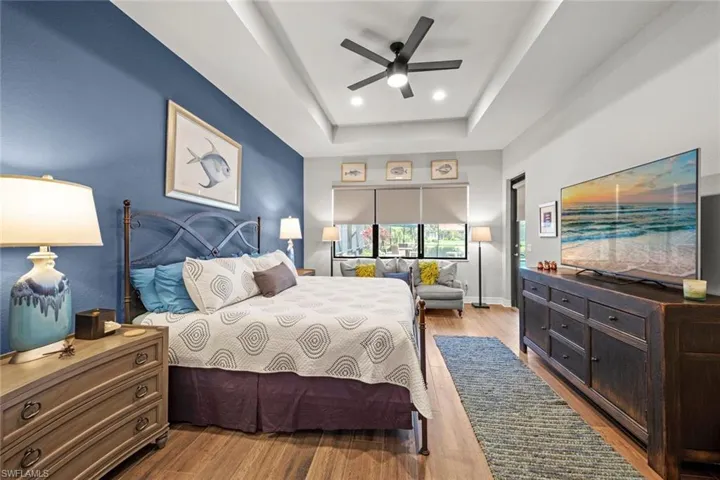 Bedroom with recessed lighting, wood finished floors, a ceiling fan, baseboards, and a tray ceiling