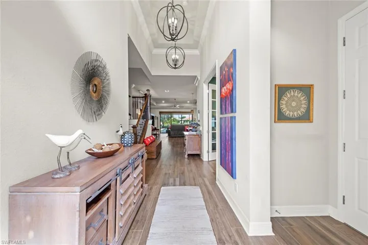Entrance foyer with crown molding, a notable chandelier, baseboards, and wood finished floors