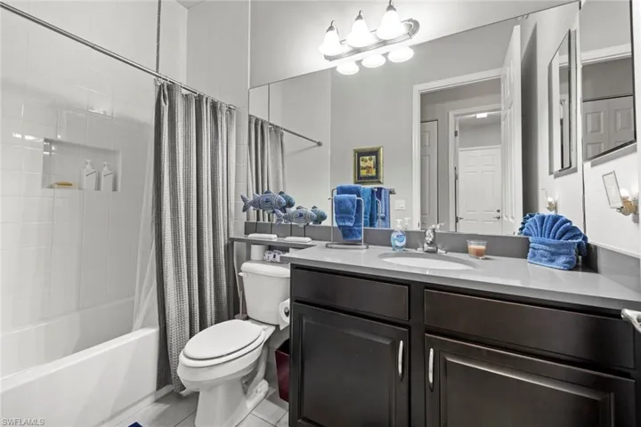 Full bath featuring tile patterned flooring, vanity, toilet, and shower / bathtub combination with curtain