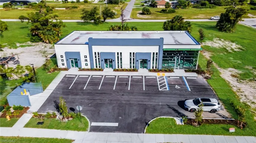 Back of house with stucco siding, uncovered parking, and a lawn