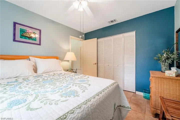 Bedroom with a ceiling fan, light tile patterned floors, and a closet
