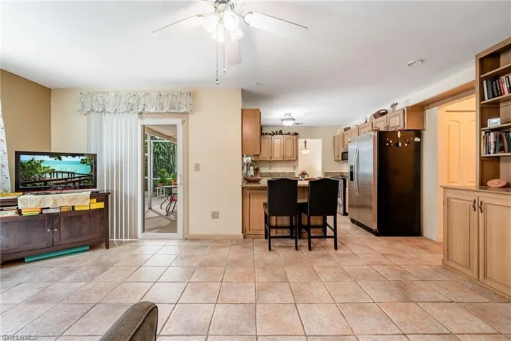 Kitchen with stainless steel appliances, a kitchen breakfast bar, a ceiling fan, a peninsula, and light tile patterned floors