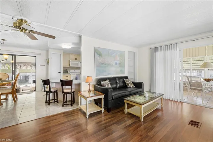 Living room featuring built in shelves, ceiling fan, wood-type flooring, and a textured ceiling