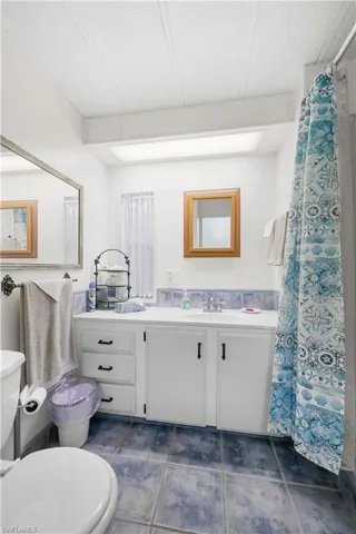 Bathroom with tile patterned flooring, vanity, toilet, and a textured ceiling