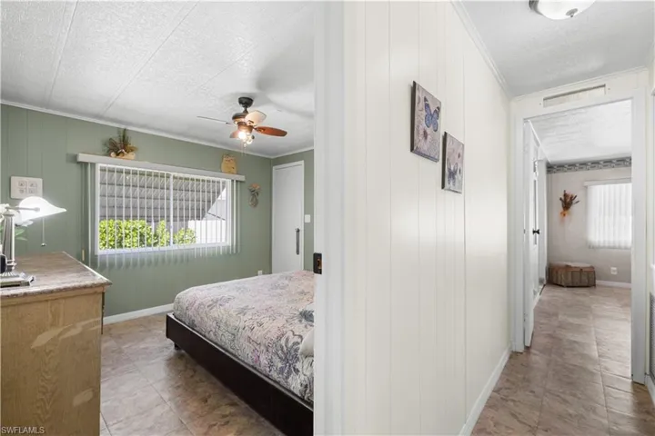 Bedroom featuring a textured ceiling, ceiling fan, and wood walls