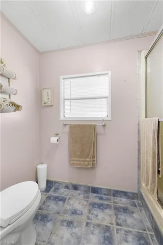 Bathroom with tile patterned floors, a textured ceiling, toilet, and a shower with shower door