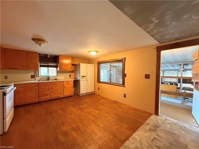 Kitchen with white appliances, light countertops, wood finish cabinets, and light wood finished floors
