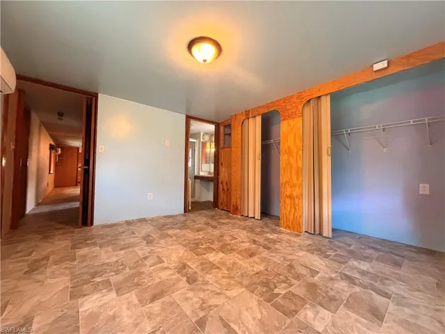 Unfurnished bedroom with stone finish floors and two closets