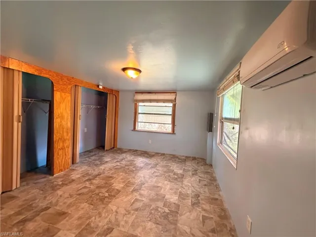 Unfurnished bedroom featuring stone finish floors, multiple closets, and a wall mounted mini split