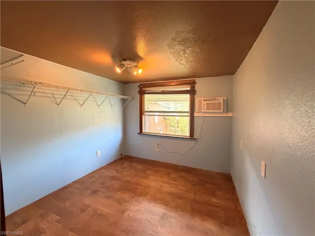 Spare room with a textured wall, a textured ceiling, and wood finished floors