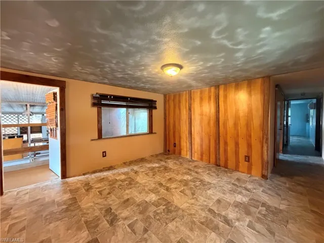 Unfurnished room with stone finish flooring, plenty of natural light, wooden walls, and a textured ceiling
