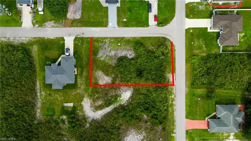 Vacant corner lot featuring natural ground cover, street frontage, and established neighboring properties