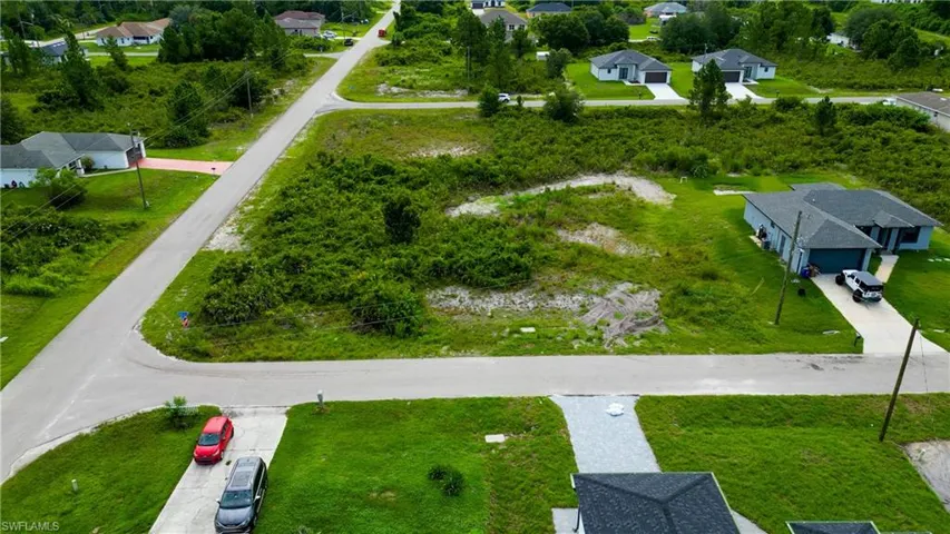 Expansive corner lot featuring a cleared building site, direct road frontage, and a surrounding of natural vegetation