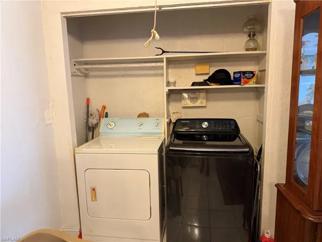 Laundry area with a textured wall, tile patterned floors, and separate washer and dryer