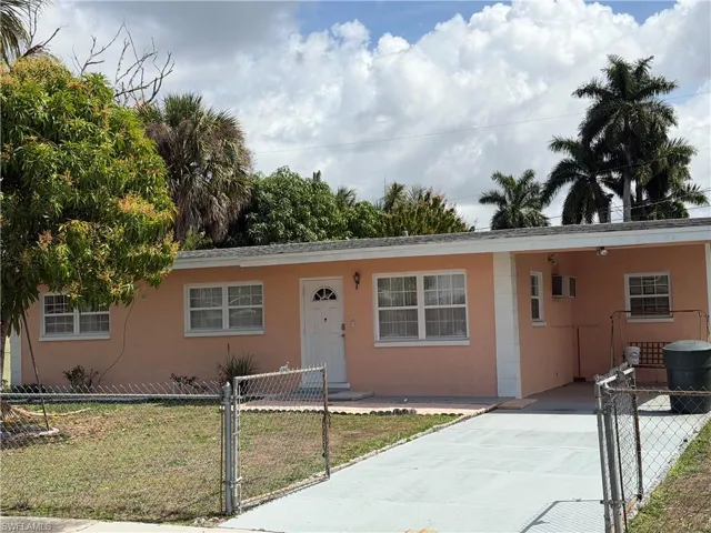 View of front of home featuring a gate, a carport, a fenced front yard, stucco siding, and concrete driveway