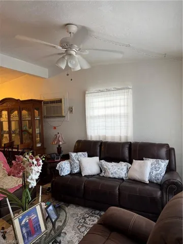 Living room with a textured wall, a textured ceiling, and ceiling fan