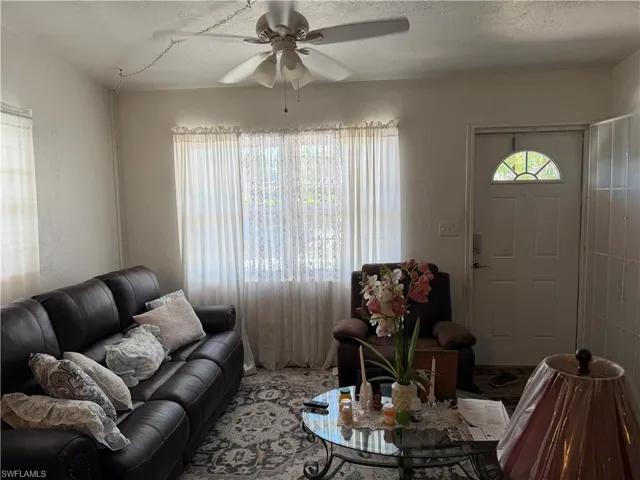 Living area featuring a ceiling fan, a textured ceiling, and a textured wall