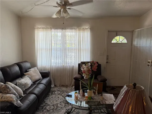 Living area with ceiling fan, a textured ceiling, and a textured wall