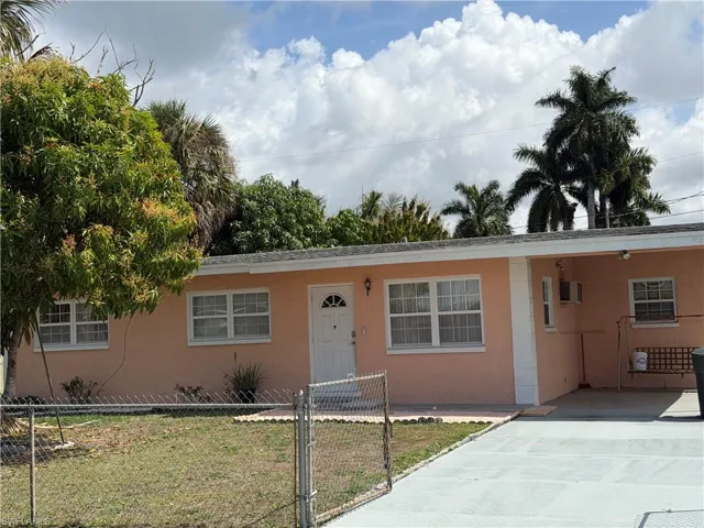 Ranch-style home with an attached carport, a gate, stucco siding, and driveway