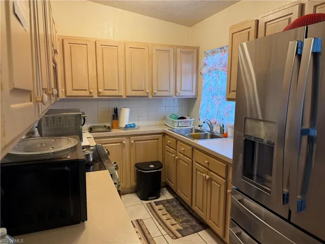 Kitchen with stainless steel refrigerator with ice dispenser, light countertops, a textured ceiling, backsplash, and electric range
