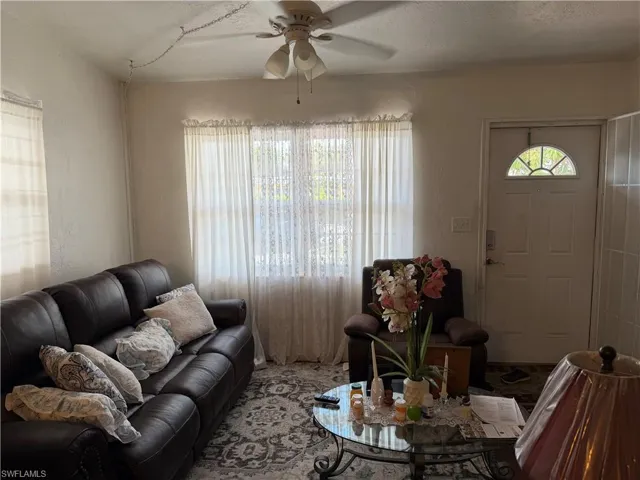 Living area featuring ceiling fan, a textured wall, and a textured ceiling