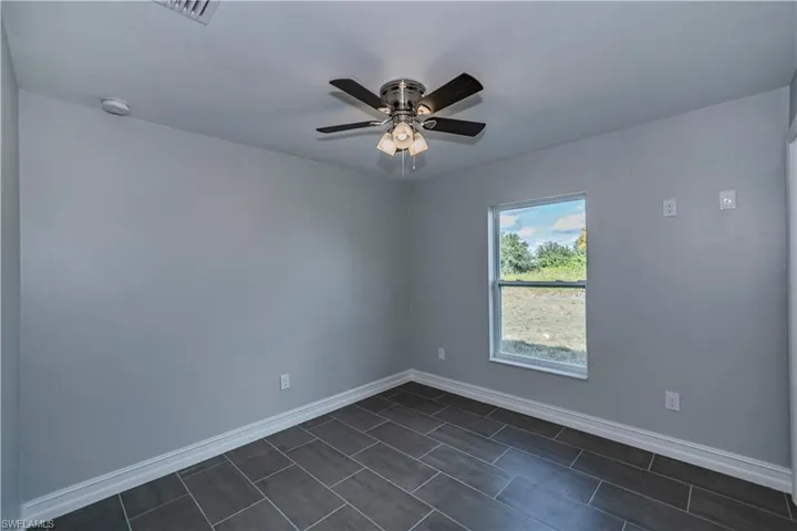 Tiled empty room featuring ceiling fan