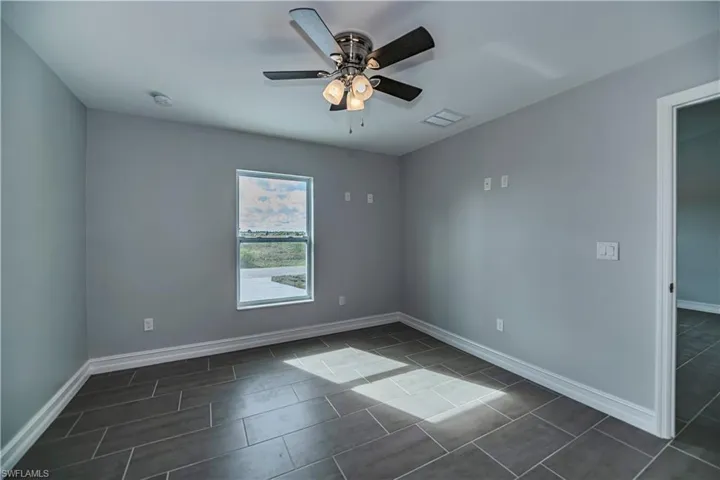 Tiled empty room featuring ceiling fan