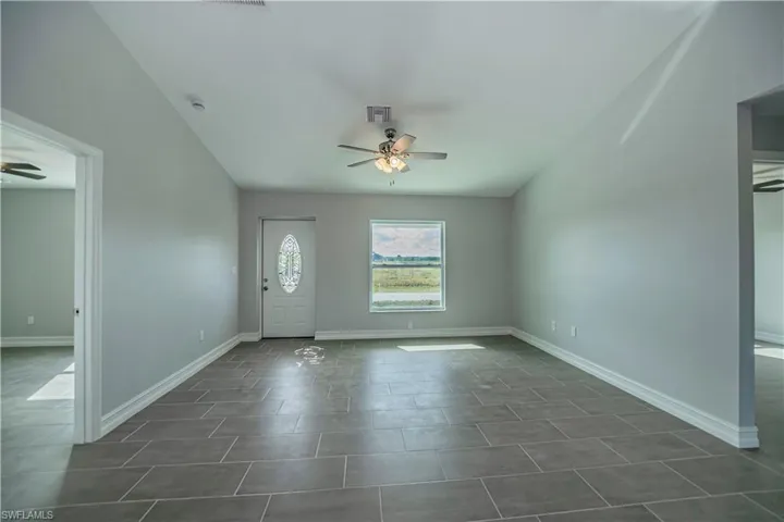 Empty room with dark tile flooring and ceiling fan