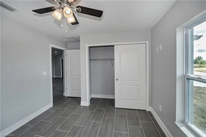Unfurnished bedroom with a closet, multiple windows, and ceiling fan