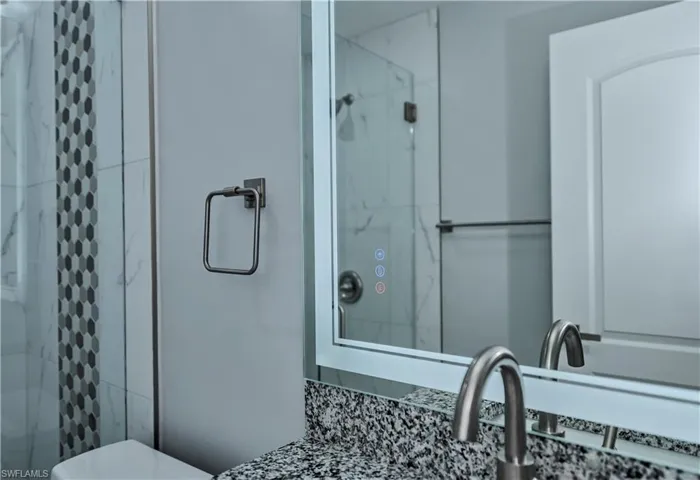 Bathroom featuring a shower with door and toilet
