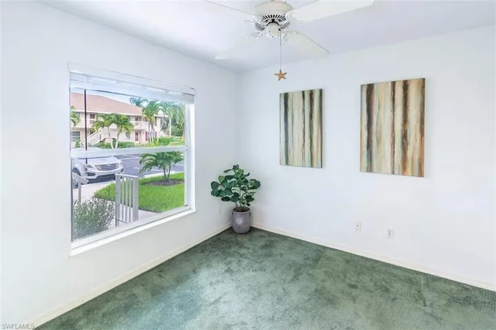 Spare room featuring dark colored carpet and ceiling fan