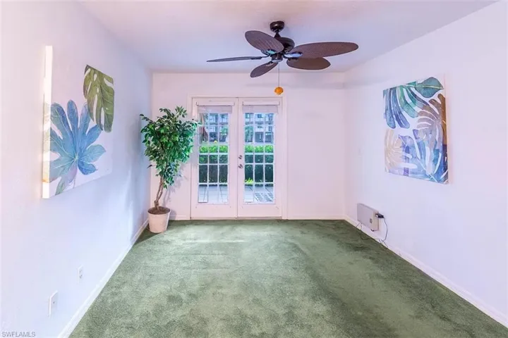 Carpeted spare room featuring ceiling fan and french doors