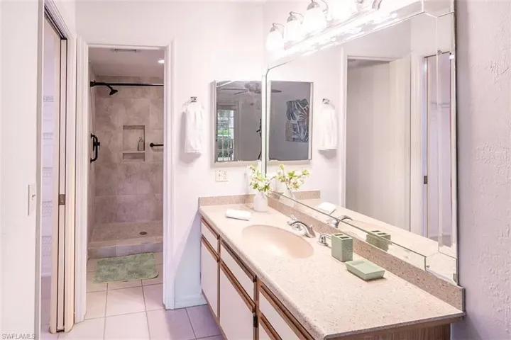 Bathroom with tile patterned floors, a shower with shower door, and vanity