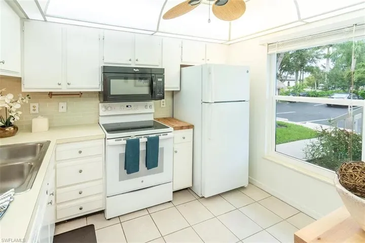 Kitchen featuring ceiling fan, tasteful backsplash, white cabinets, white appliances, and light tile patterned floors