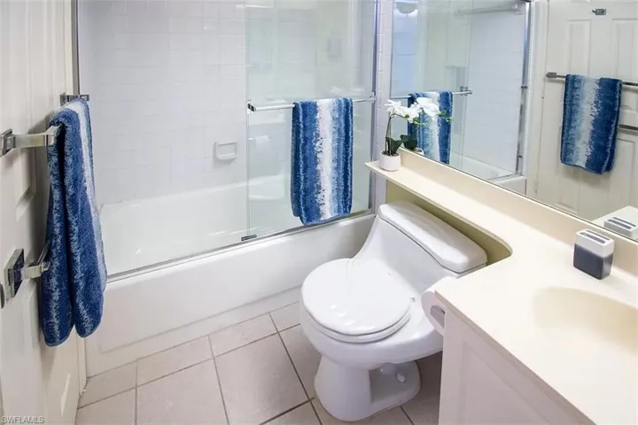 Full bathroom featuring vanity, tile patterned flooring, bath / shower combo with glass door, and toilet