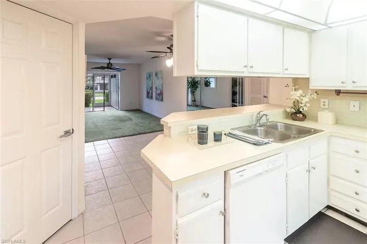 Kitchen with kitchen peninsula, light carpet, dishwasher, and ceiling fan